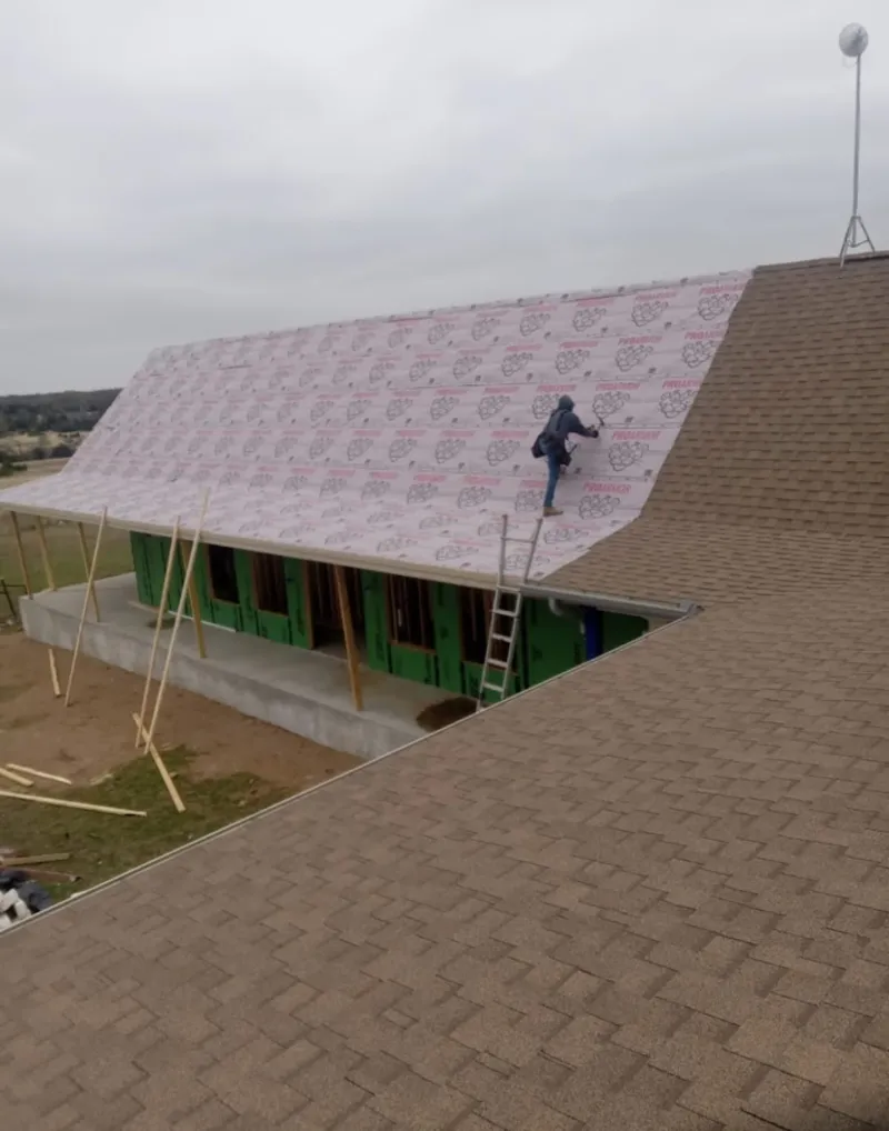 Worker preparing underlayment for a metal roof installation in La Follette